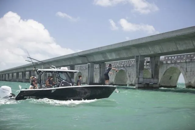 Slide: The Image of 2024 Blackfin 272CC boat cruising under a bridge on a sunny day. - 7