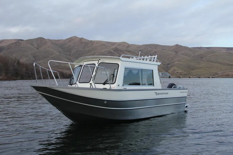 Slide: The Image of 2023 Spartan 220 Maximus Pro boat on a calm lake with mountainous background. - 15
