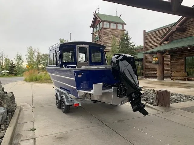 Slide: The Image of 2023 Spartan 220 Maximus Pro boat on trailer near rustic lodge. - 3