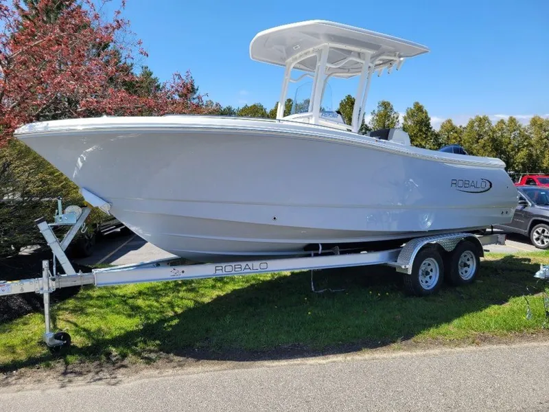 Slide: The Image of 2024 Robalo R232EX boat on a trailer, parked outdoors. - 1