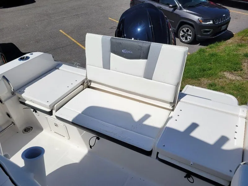 Slide: The Image of 2024 Robalo R232EX boat seating area with white cushions and storage compartments. - 15