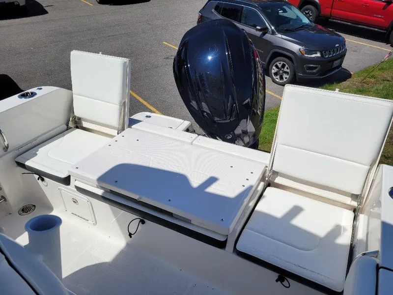 Slide: The Image of 2024 Robalo R232EX boat with white seating and outboard motor. - 17