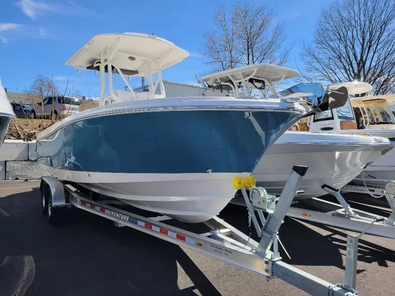 Slide: The Image of 2024 Edgewater 245 CC boat on trailer, blue hull, parked outdoors. - 2