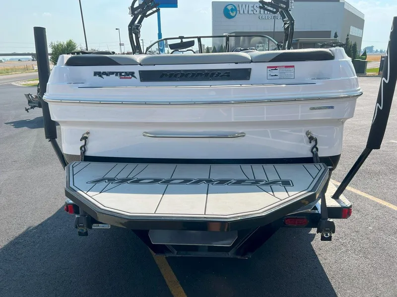 Slide: The Image of 2018 Moomba Mojo boat rear view in parking lot, showcasing swim platform. - 5