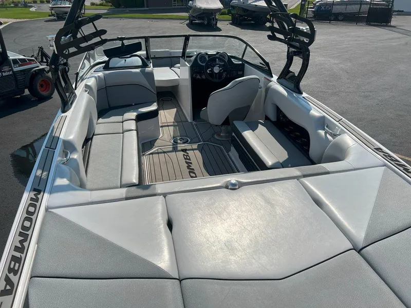 Slide: The Image of 2018 Moomba Mojo boat interior with gray seating and steering wheel, parked outdoors. - 9