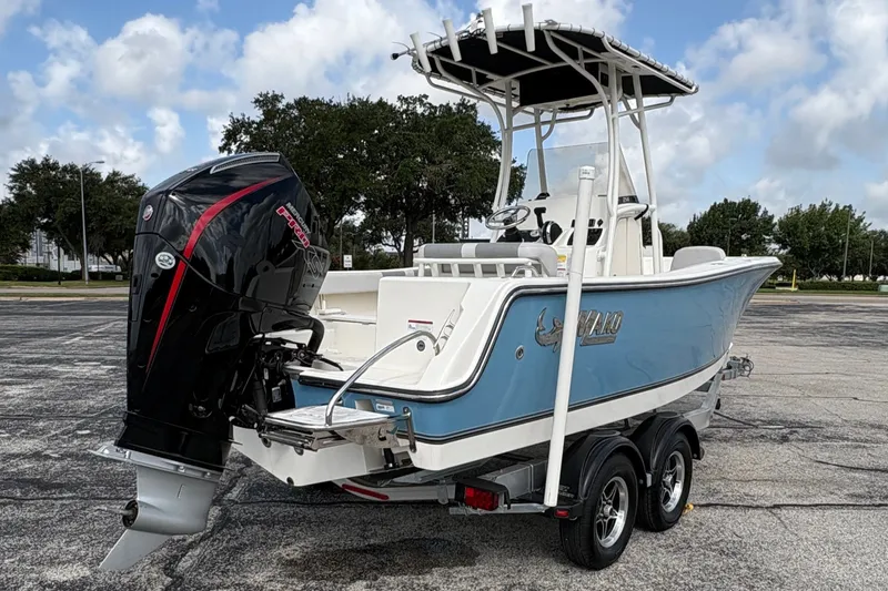 Slide: The Image of A 2024 Mako 214 Center Console boat on a trailer in a parking lot. It features an outboard motor and blue hull design. - 9