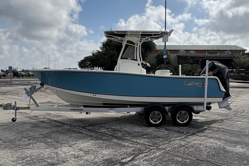 Slide: The Image of A 2024 Mako 214 Center Console boat on a trailer, featuring a blue hull and T-top. - 2