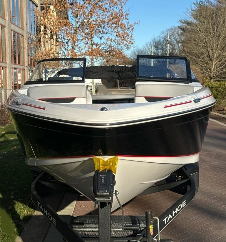 Slide: The Image of 2024 Tahoe 210 Si boat on a trailer, parked outdoors. - 2