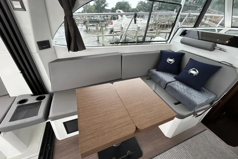 Slide: The Image of Interior of 2024 Beneteau Antares 11 with cozy seating and wooden table. - 7