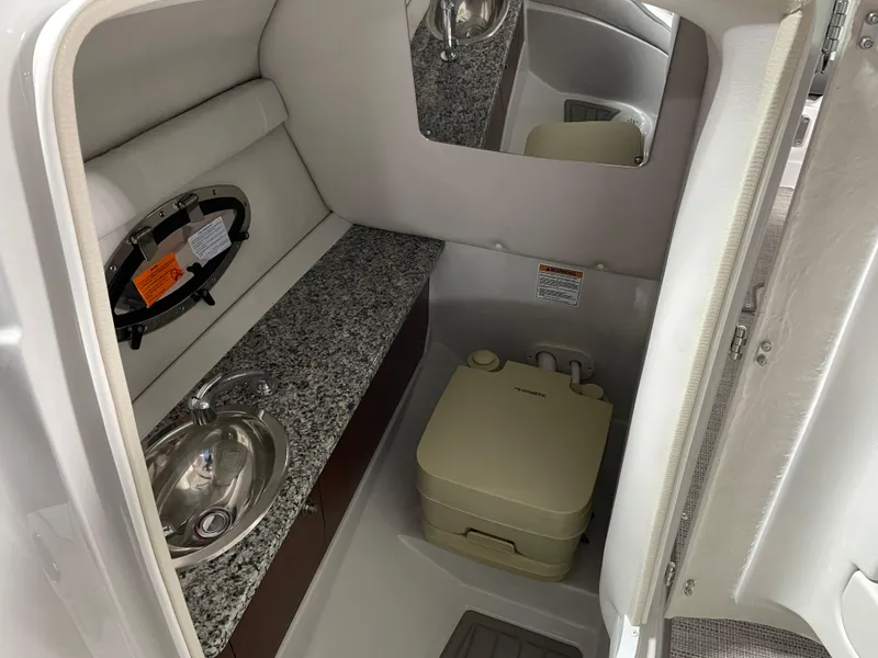 Slide: The Image of 2024 Crownline Eclipse E260 XS boat interior bathroom with sink and portable toilet. - 13