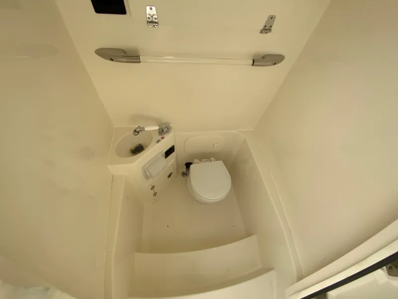 Slide: The Image of 2025 Cobia 240 Center Console boat bathroom interior with toilet and sink. - 28