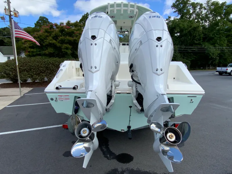 Slide: The Image of 2025 Cobia 240 Center Console with dual outboard engines in a parking lot. - 8