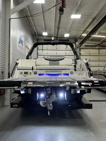 Slide: The Image of 2024 Chaparral 287 SSX boat in a showroom, rear view with illuminated swim platform. - 8