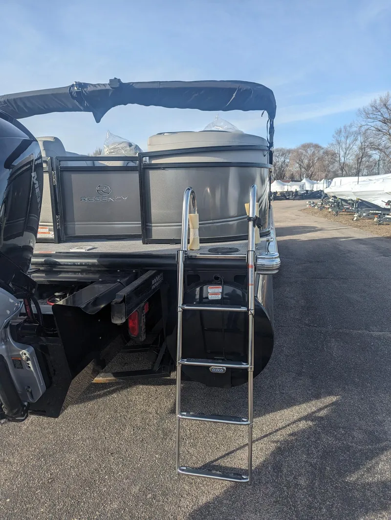 Slide: The Image of 2024 Regency 230 LE3 pontoon boat with ladder, parked outdoors. - 2