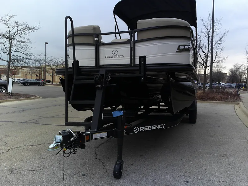 Slide: The Image of 2024 Regency 230 DL3 pontoon boat on a trailer in a parking lot. - 1