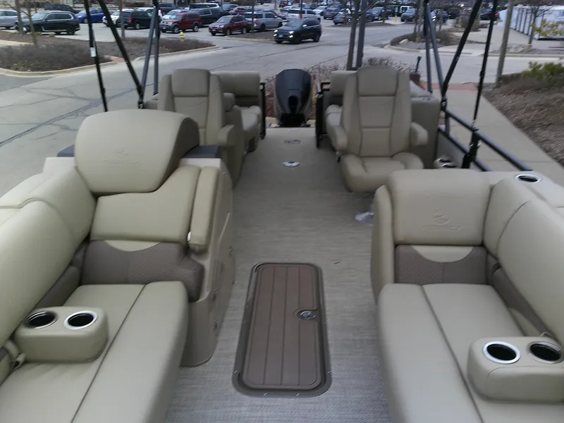 Slide: The Image of 2024 Regency 230 DL3 pontoon boat interior with beige seating and cup holders. - 5
