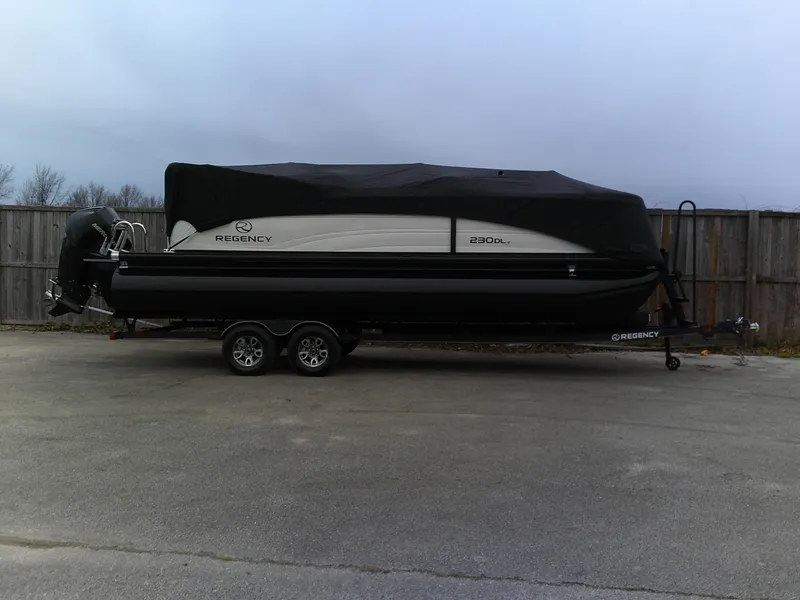 Slide: The Image of 2024 Regency 230 DL3 pontoon boat on a trailer, covered with a black tarp. - 8