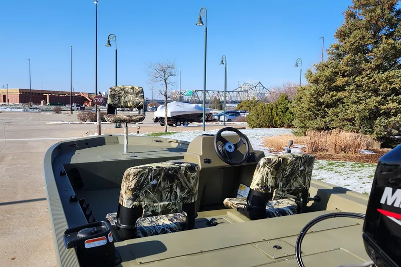 Slide: The Image of 2024 Tracker Grizzly 1754 SC boat with camo seats, parked outdoors. - 3