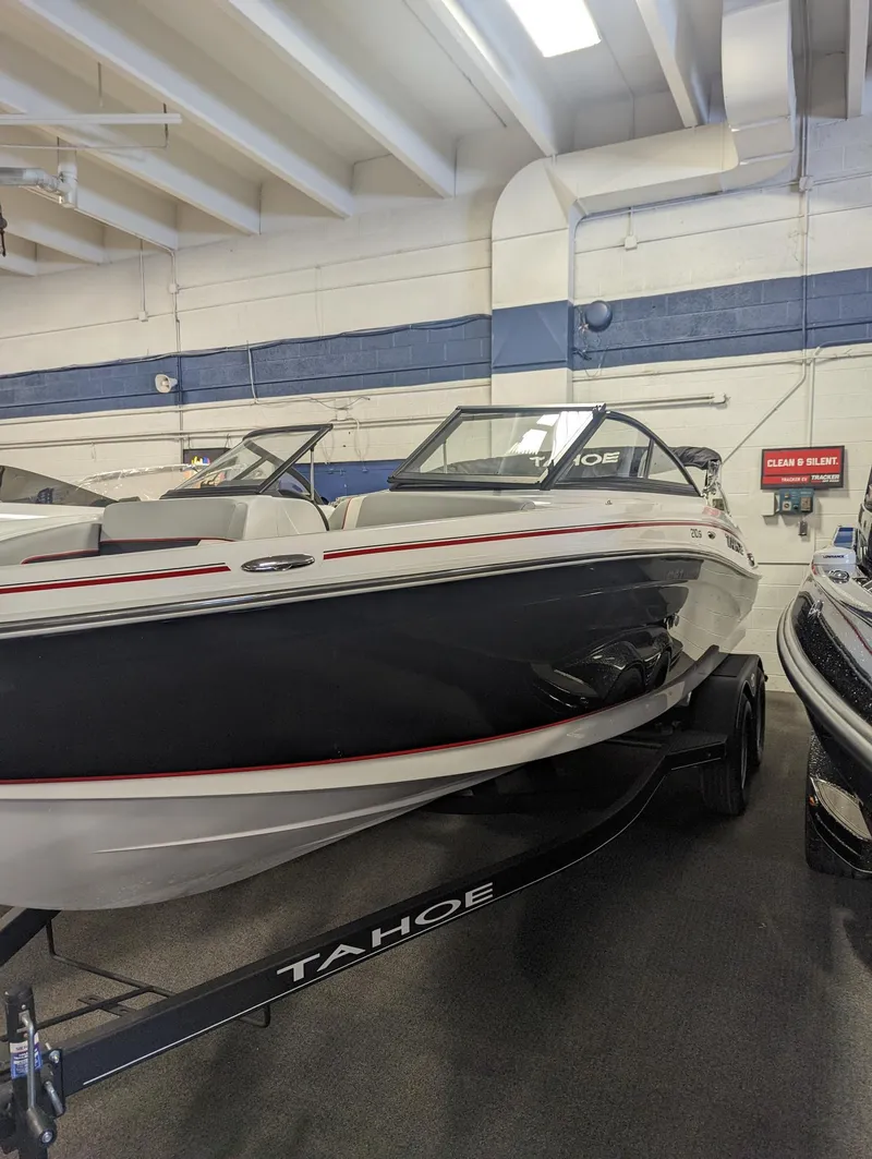 Slide: The Image of 2024 Tahoe 210 Si boat displayed indoors on a trailer. - 2