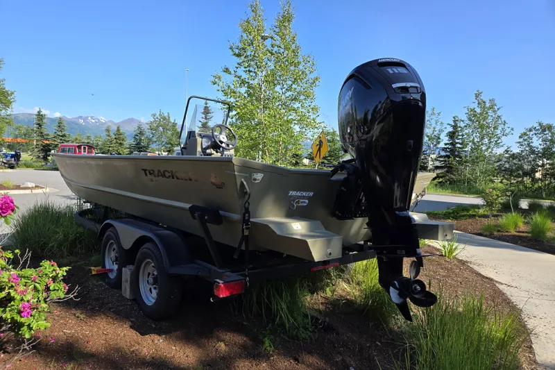 Slide: The Image of 2024 Tracker Grizzly 2072 CC boat on trailer, parked outdoors with scenic mountain backdrop. - 3