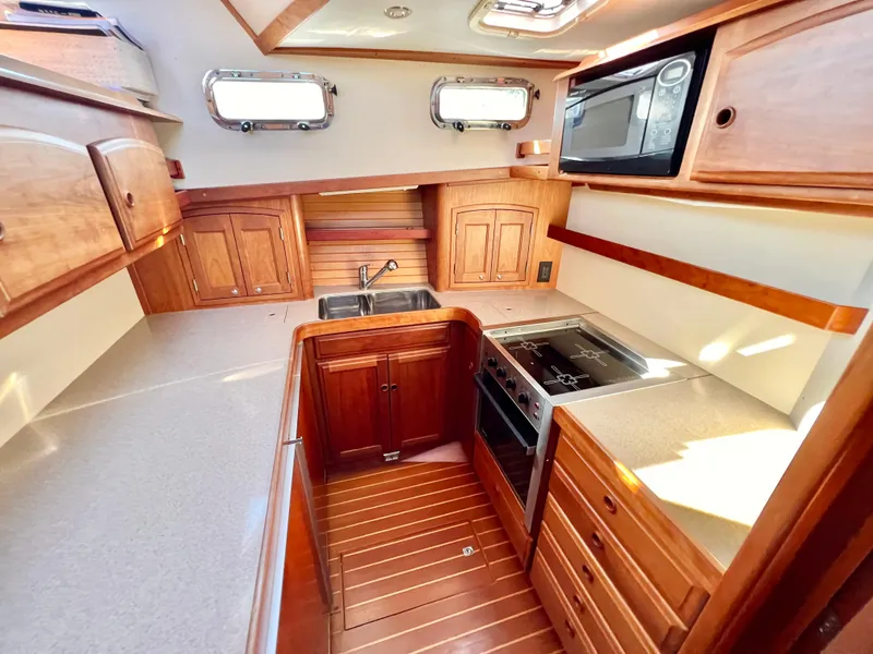 Slide: The Image of 2001 Sabre Sabreline 47 yacht kitchen with wooden cabinetry, stove, microwave, and sink. - 18