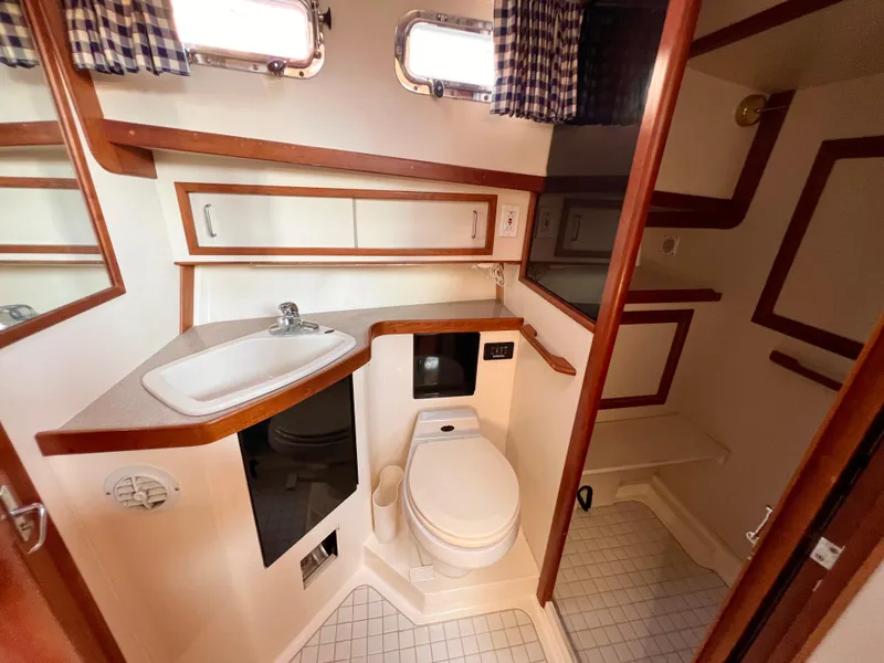 Slide: The Image of 2001 Sabre Sabreline 47 yacht bathroom with sink, toilet, and storage cabinets. - 9