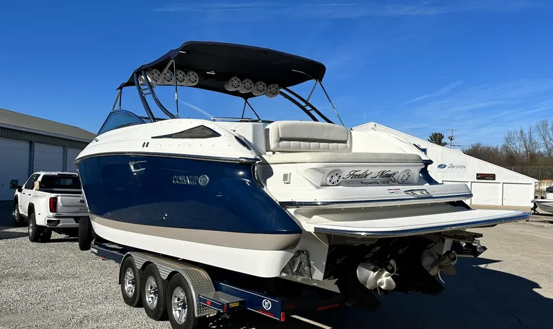 Slide: The Image of 2006 Cobalt 323 boat on a trailer, blue and white exterior, parked outdoors. - 2