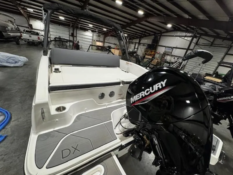 Slide: The Image of 2024 Bayliner DX2000 boat with Mercury outboard motor in a warehouse. - 6