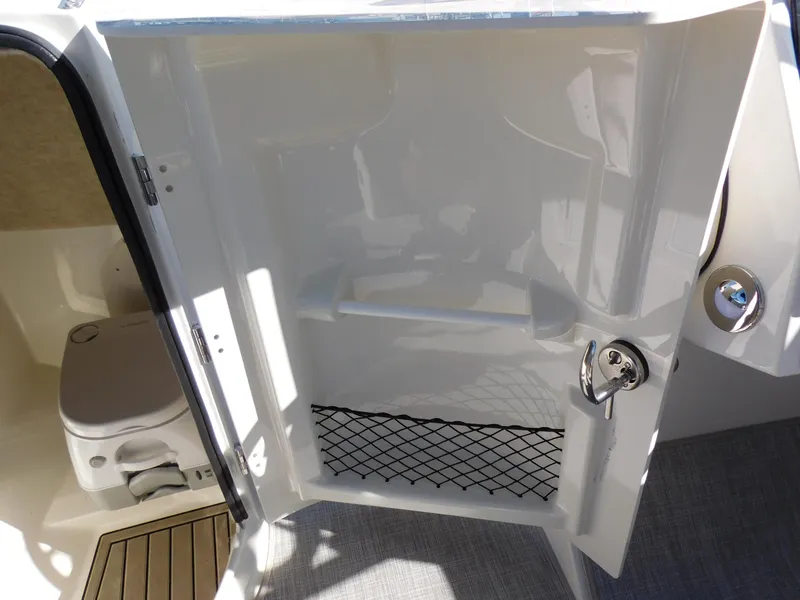 Slide: The Image of 2024 Stingray 231 DC boat interior with bathroom and storage compartment. - 27