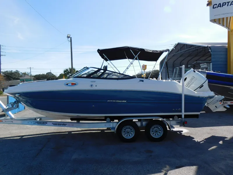 Slide: The Image of 2024 Stingray 231 DC boat on a trailer, side view, blue and white color. - 3