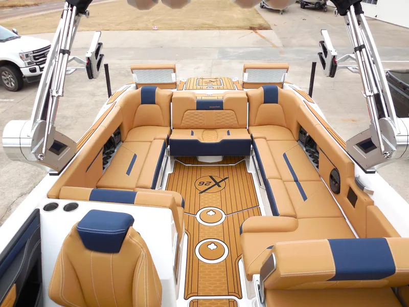 Slide: The Image of 2024 MasterCraft X26 boat interior with tan and navy seating, spacious layout, and modern design. - 10