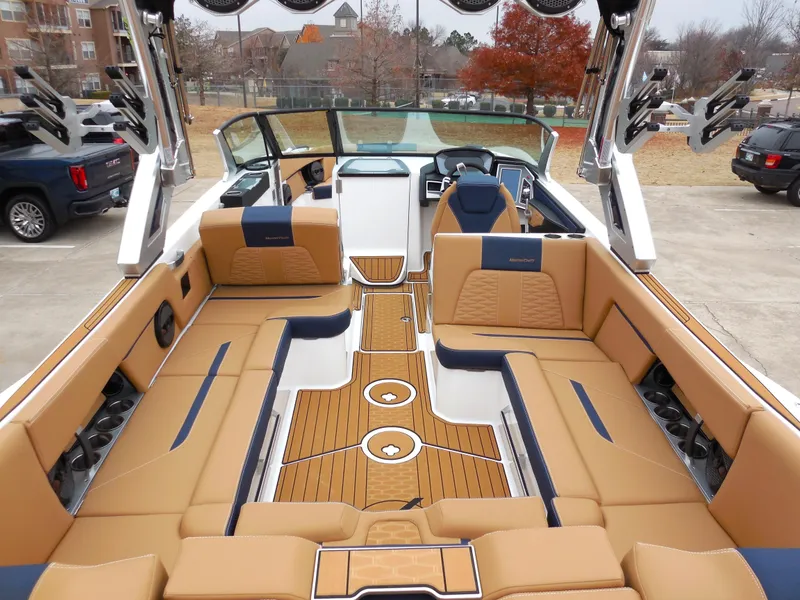 Slide: The Image of 2024 MasterCraft X26 boat interior with tan and navy seating, teak flooring, and modern dashboard. - 5