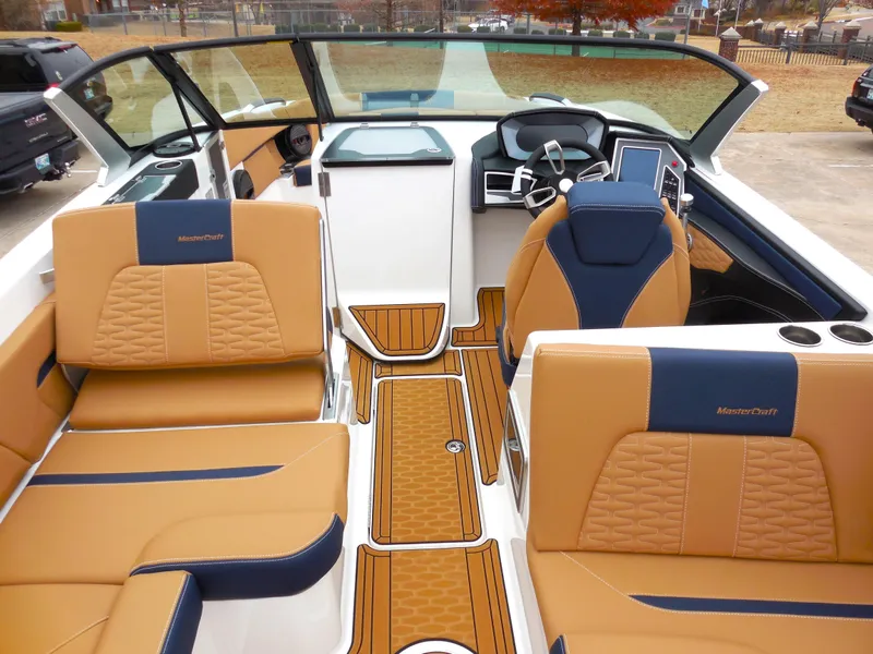 Slide: The Image of 2024 MasterCraft X26 boat interior with tan and blue seating, modern dashboard, and teak flooring. - 6