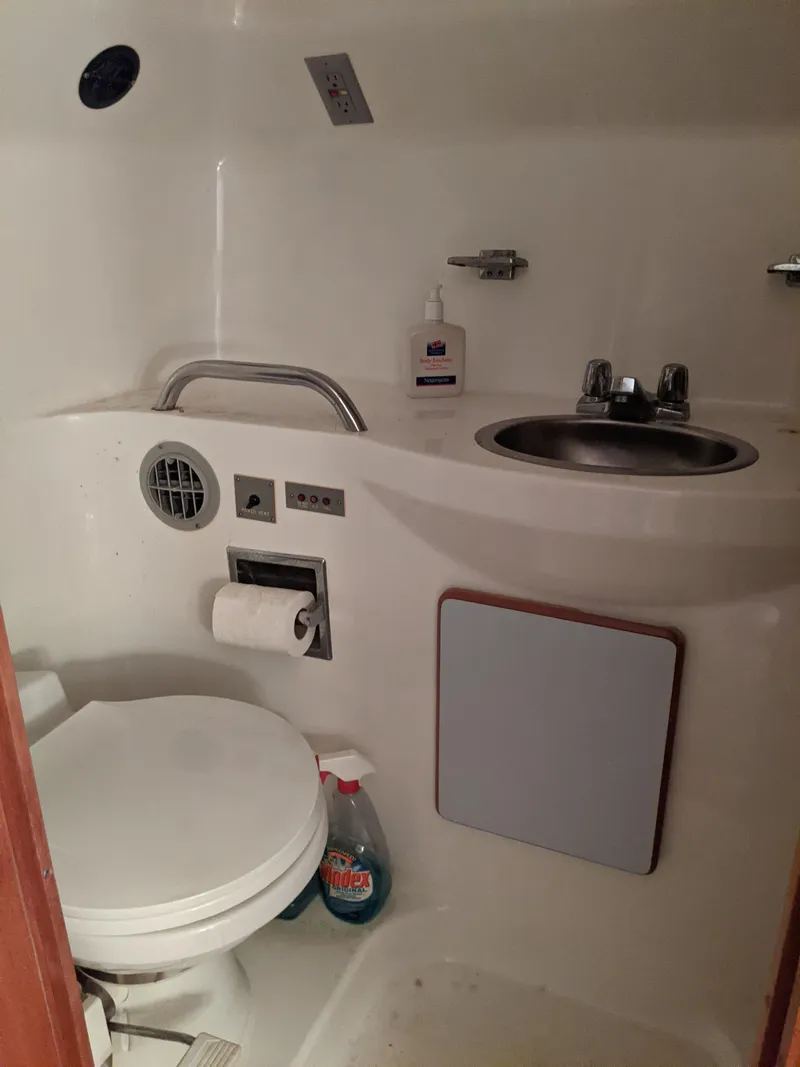 Slide: The Image of 1989 Sea Ray 380 Aft Cabin bathroom with sink, toilet, and cleaning supplies. - 19