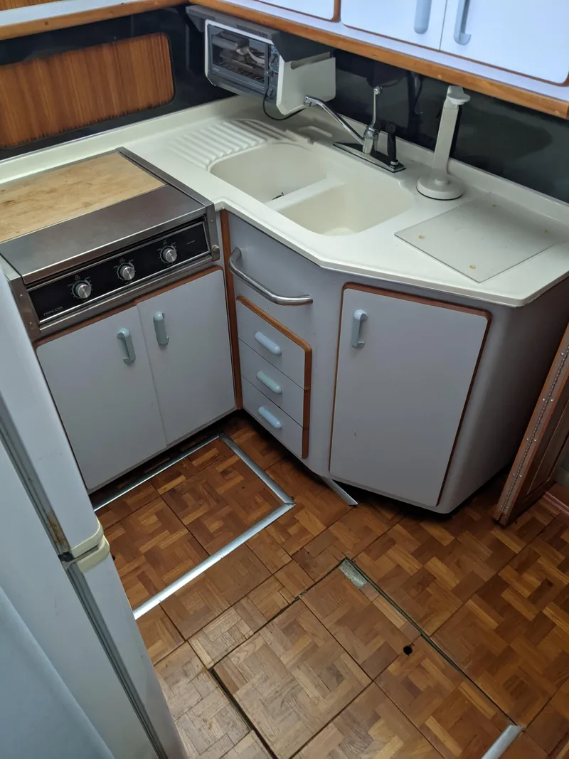 Slide: The Image of 1989 Sea Ray 380 Aft Cabin kitchen with stove, sink, and wooden flooring. - 29