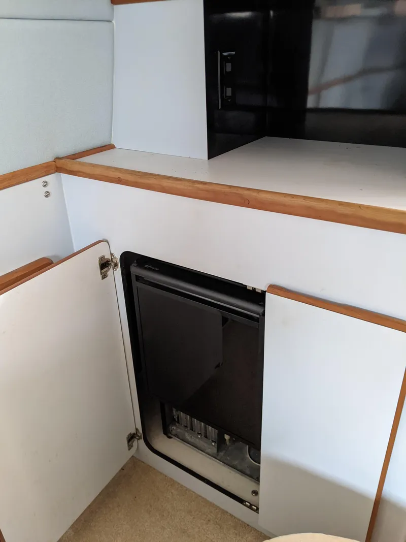 Slide: The Image of 1989 Sea Ray 380 Aft Cabin interior with open cabinet and built-in appliance. - 32