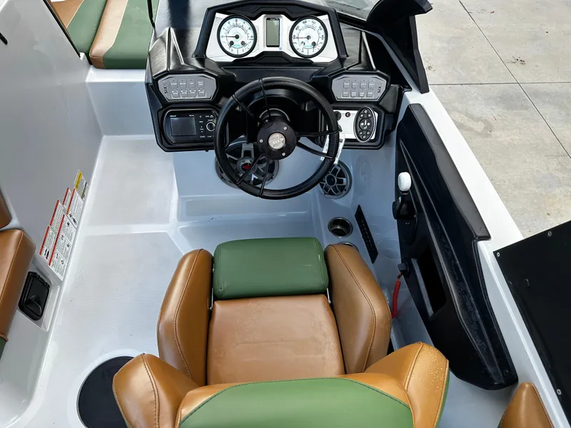 Slide: The Image of 2021 Axis T22 boat cockpit with steering wheel, gauges, and brown-green seats. - 22