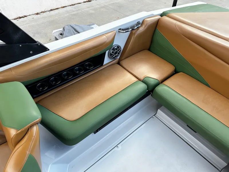 Slide: The Image of 2021 Axis T22 boat interior with green and tan seating, cup holders, and speaker. - 26