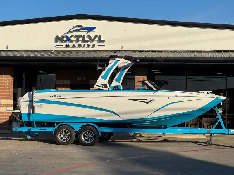Slide: The Image of 2024 Tigé Z3 boat in blue and white on trailer outside NXT LVL Marine. - 2