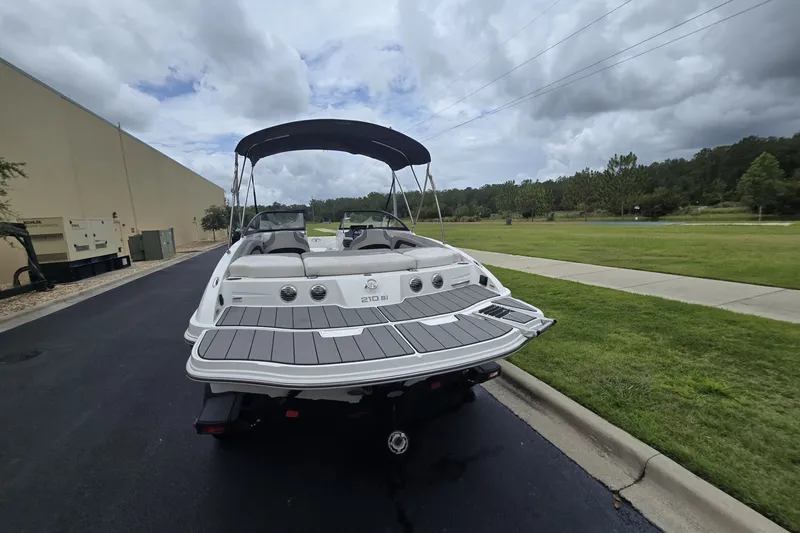Slide: The Image of 2024 Tahoe 210 Si boat with canopy on a trailer, parked outdoors. - 68