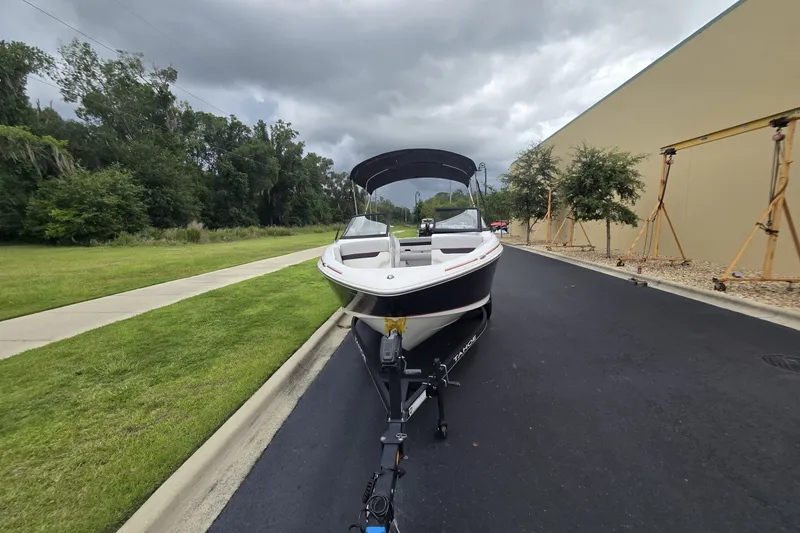 Slide: The Image of 2024 Tahoe 210 Si boat on trailer, parked on a paved road under cloudy skies. - 4