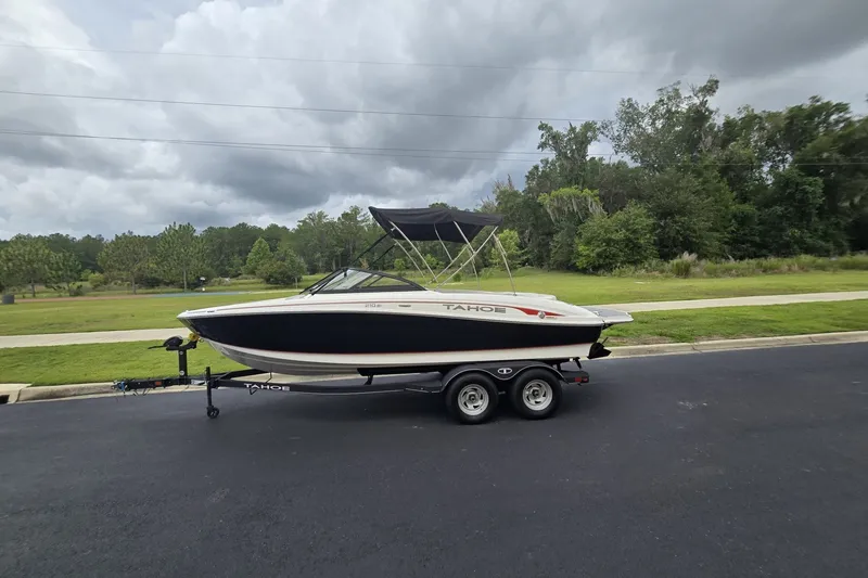 Slide: The Image of 2024 Tahoe 210 Si boat on trailer, parked on a road with cloudy sky. - 69
