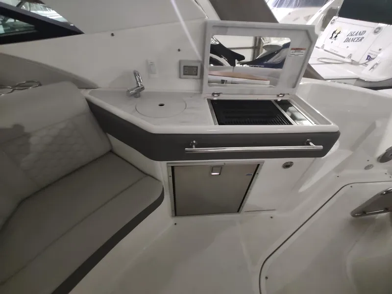 Slide: The Image of 2023 Sea Ray 320 Sundancer boat interior with kitchenette and seating area. - 19