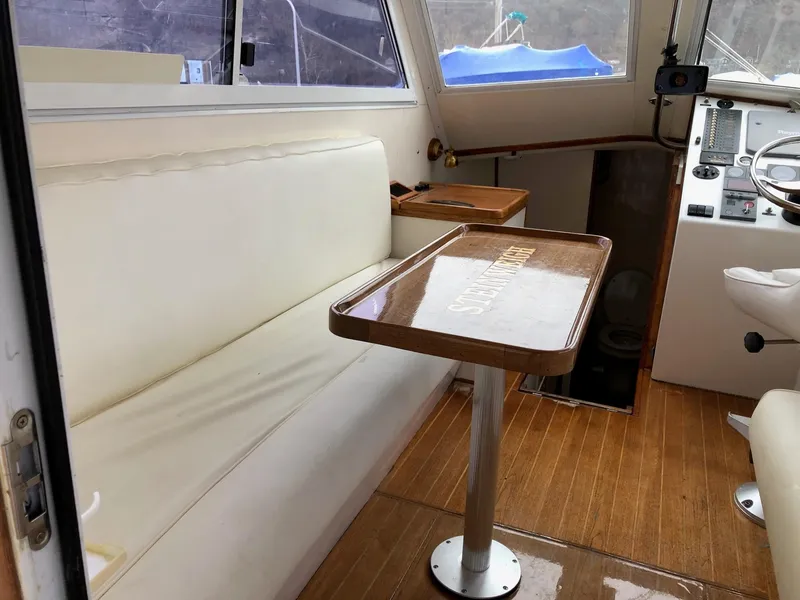 Slide: The Image of Interior of a 2005 Morgan 31 boat with white seating and wooden table. - 10