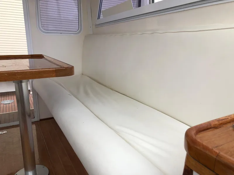 Slide: The Image of Interior seating area of a 2005 Morgan 31 boat with white cushions and wooden table. - 17