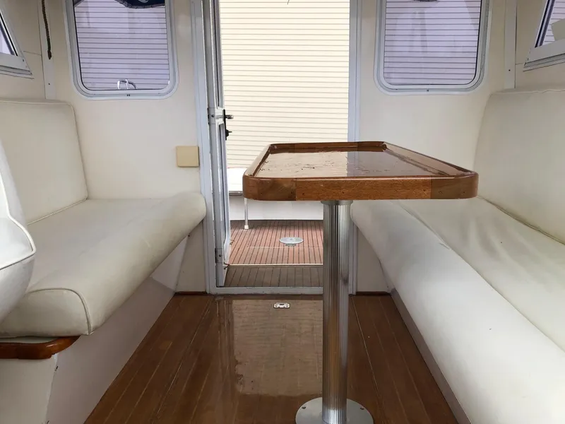 Slide: The Image of Interior of 2005 Morgan 31 boat with white seating and wooden table. - 18