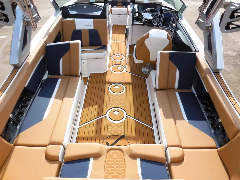Slide: The Image of 2024 MasterCraft X24 boat interior with tan and navy seating, teak flooring, and modern dashboard. - 6