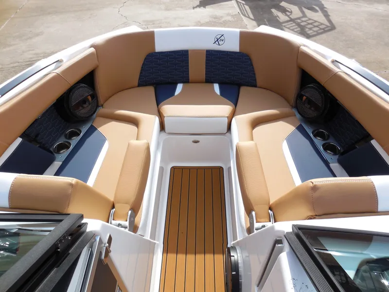 Slide: The Image of 2024 MasterCraft X24 boat interior with tan and blue seating, teak flooring, and built-in speakers. - 8