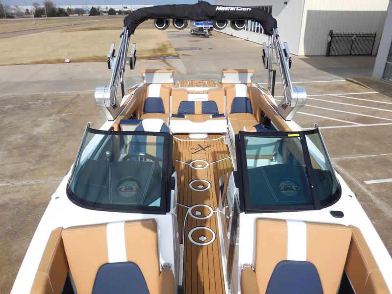 Slide: The Image of 2024 MasterCraft X24 boat with tan and white interior, docked on concrete. - 9