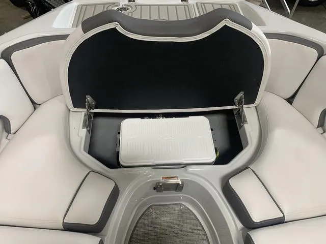 Slide: The Image of 2024 Crownline E255 boat with open storage compartment and cushioned seating. - 15
